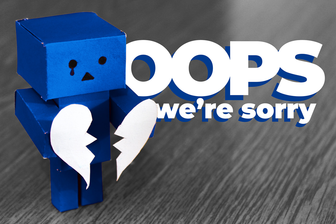 A cute but sad little blue robot holding a broken heart, with the words "Oops, we're sorry!"