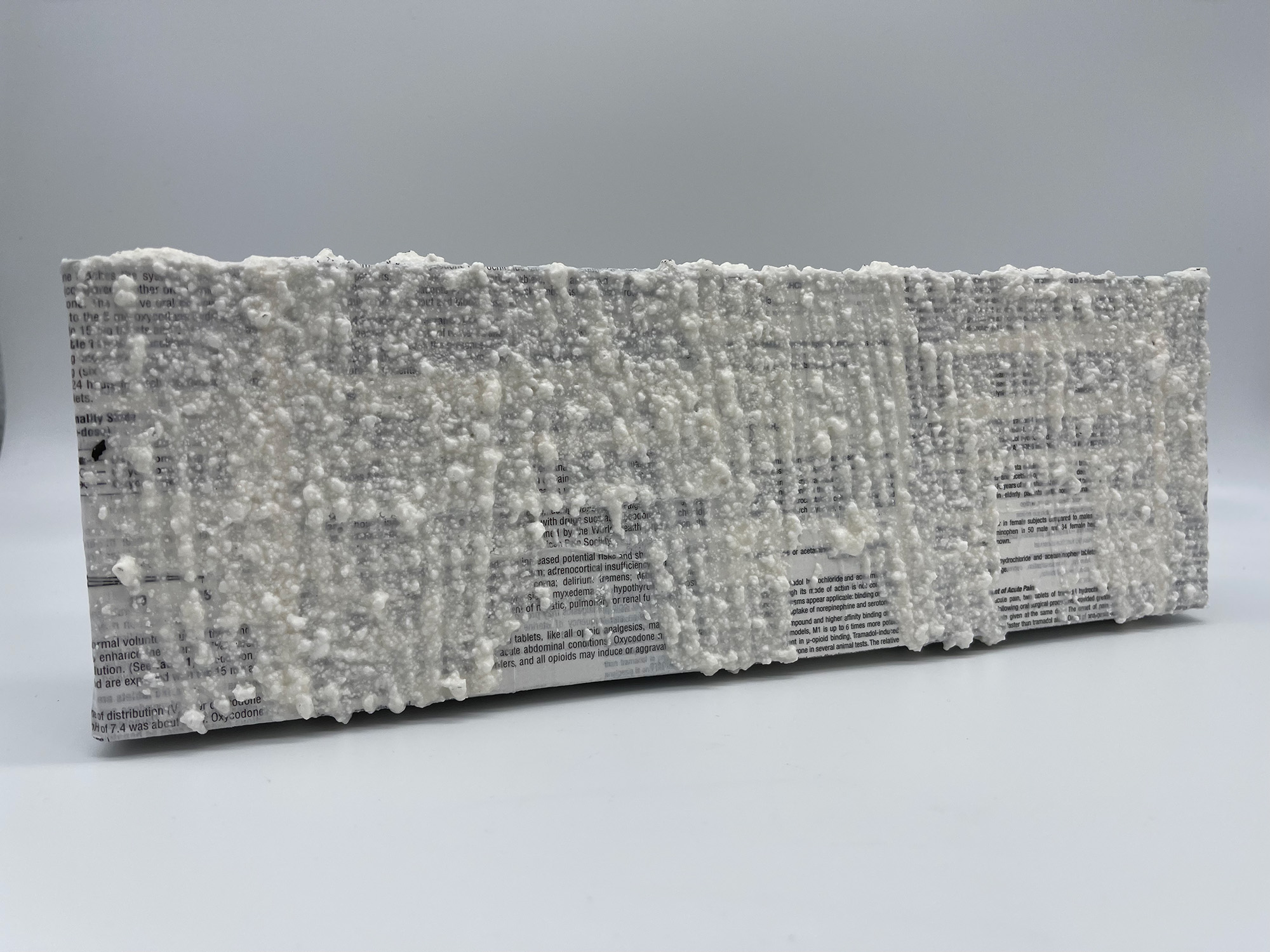 An original mixed media painting by H.M.A. Lawver, 4/5. Created using crushed tylenol mixed with gesso & acrylic, painted atop a canvas covered in collaged narcotic drug information inserts. 