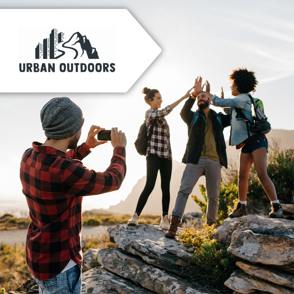 A promotional image we created to promote Urban Outdoors! Image shows a group of friends out hiking; one man in a red flannel shirt is taking a photo of three friends, posing on top of a rock, while high fiving each other.