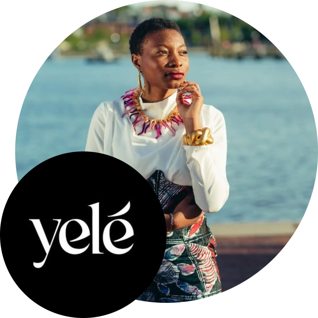 Yele Stitches Logo & promotional images featuring founder, Yele Oladeinde. Yele is posing against a fence by a waterfront, looking off to the right, her fingers gently placed against her chin. She's wearing a bright & colorful statement necklace over a white blouse, and a colorful printed skirt. 